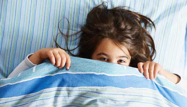 Daughter lying in bed with a blanket on her face