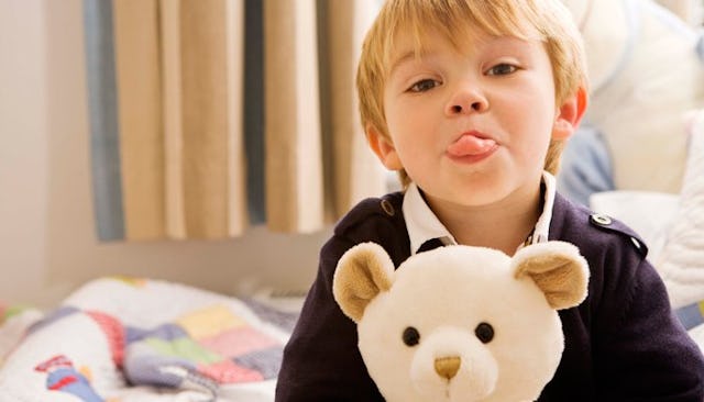 A young boy holding a teddy bear and sticking his tongue out who needs to learn how to show respect