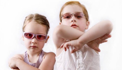 Two girls wearing vintage sunglasses posing with crossed arms