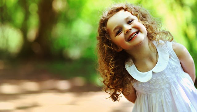 Little curly-haired girl dressed in a white dress