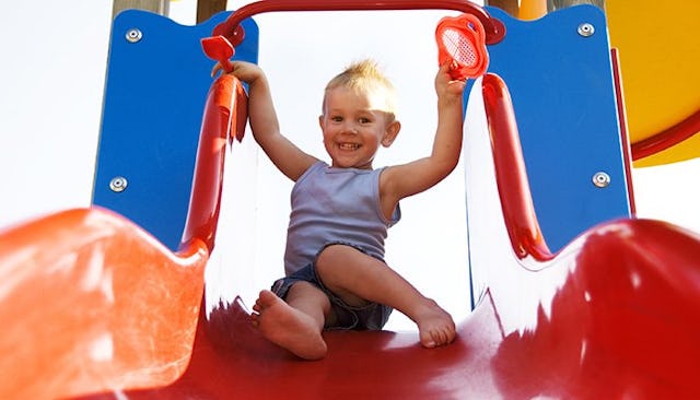 A little boy going down a slide at a playground