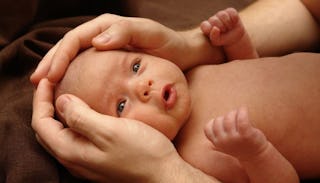 A father caresses his newborn baby's head