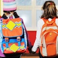 Two middle school girls going to school carrying backpacks