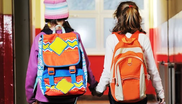 Two middle school girls going to school carrying backpacks