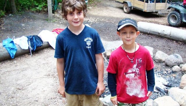 Two boys posing for a photo in a camp