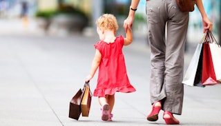 A mother and her daughter walking down the street while carrying shopping bags