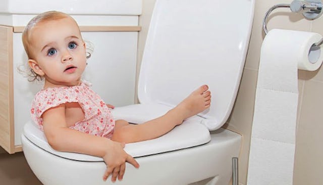 A baby girl sitting inside a toilet