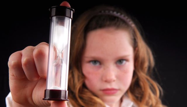 A girl holding an hourglass clock which signifies she's running out of patience