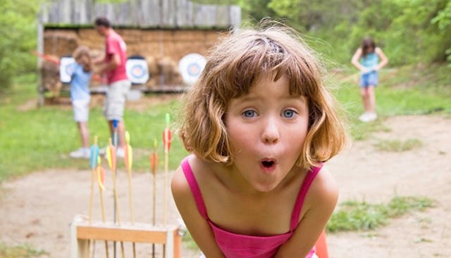A girl making a funny facial expression during a day at a summer camp's archery training