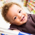 A smiling baby in the shopping cart in the supermarket 