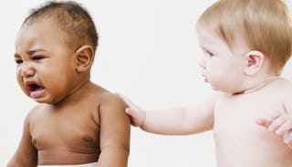 A baby putting his hand on the shoulder of a crying baby, comforting him.