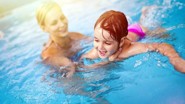 A mom teaching her daughter how to swim at the pool.