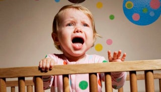 A baby crying in a crib