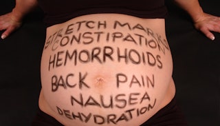 A pregnancy belly with all of the pregnancy symptoms written on it.