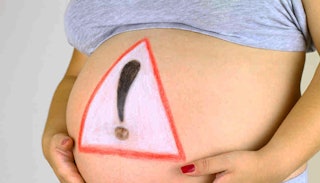 A close-up of a pregnant woman's belly with a significant danger sign drawn on it.