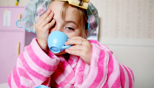 A girl in a dark-pink and light-pink striped house cape with hair yellow hair rollers drinking from ...