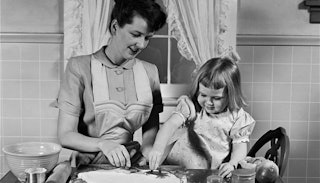 A vintage photo of a stay at home mom making cookies in the kitchen with her daughter in black and w...