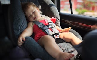 A baby boy sleeping in a baby seat inside a car