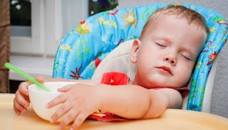 A toddler boy who is just like a frat boy sleeping during mealtime in his blue chair