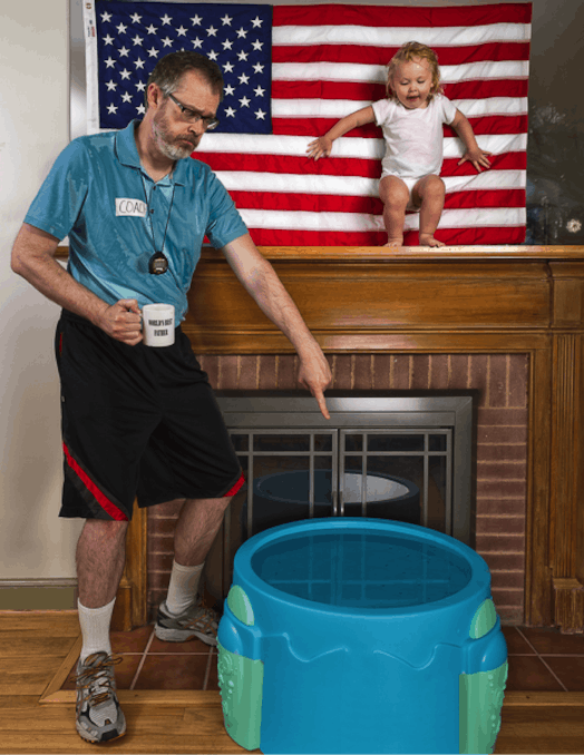 Father wearing sports gear and holding a cup pointing at a small pool to his daughter at the ledge a...