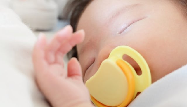 A newborn baby sleeping with yellow pacifier