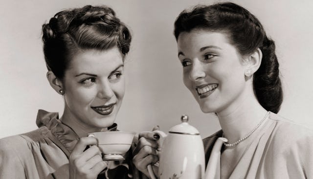 Two retro moms holding a tea kettle and a teacup, smiling while looking at each other