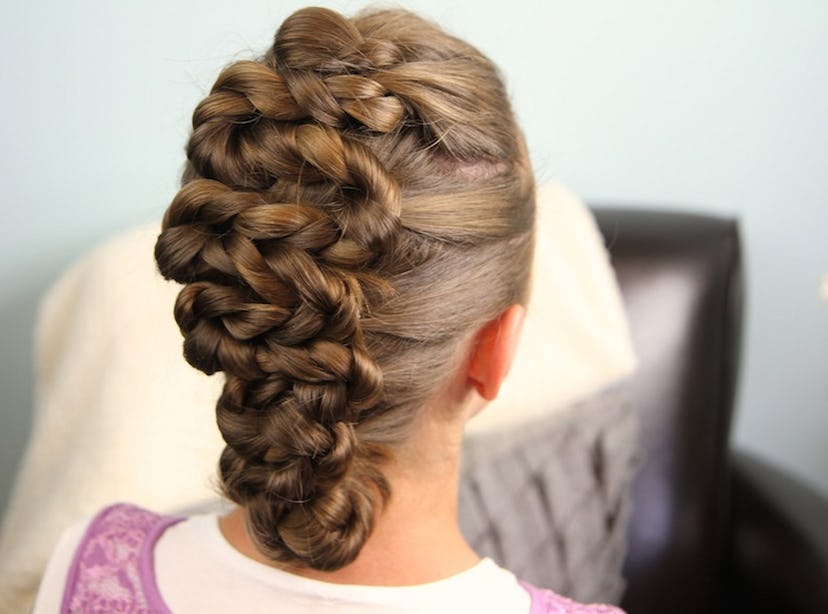 The back of a brown-haired girl who has a large braid on the back of her head and is wearing a pink ...