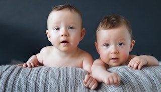 Baby twin boys on a grey blanket