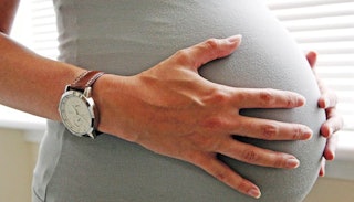 A pregnant woman holding her belly with her hands