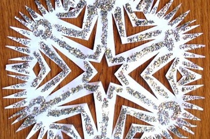 A glitter white snowflake made from paper on a wooden desk