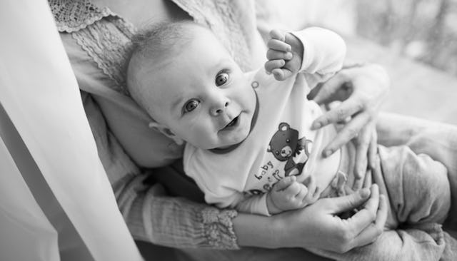 A baby sitting on the lap being held by her great mom in black and white