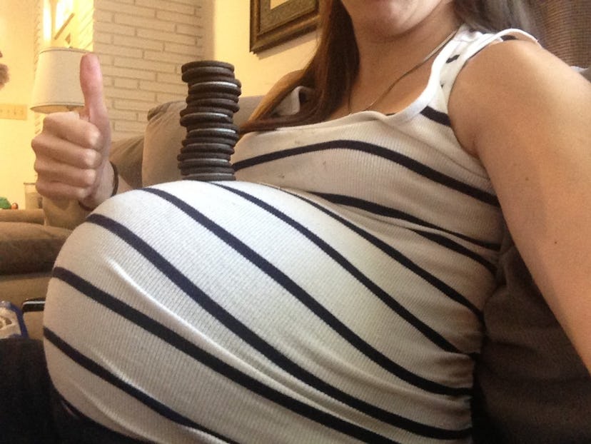 Pregnant Catherine Naja taking a picture of her stomach with Oreos stacked on top of it while showin...