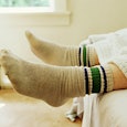 Close-up photograph of men's feet in grey and green socks while he is laying in his bed 