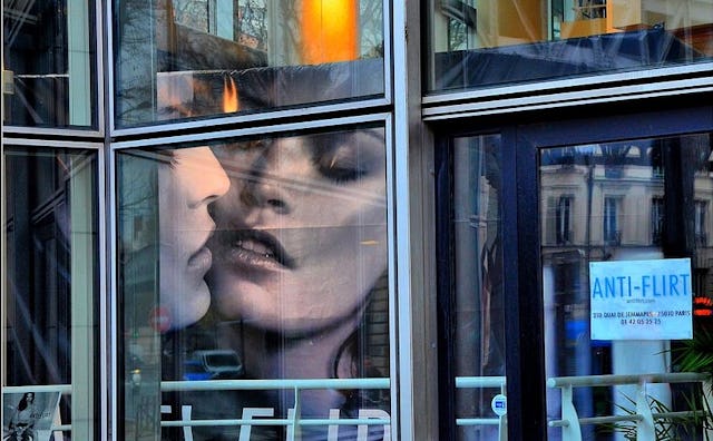 The exterior of a building with glass windows with an anti-flirt paper sign placed on the glass
