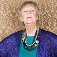 Mother-in-law posing in stacked necklaces and in a blue coat