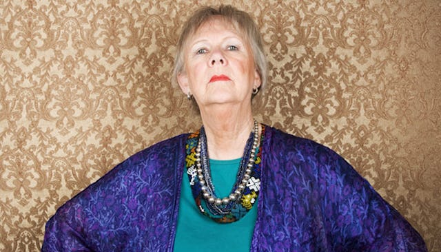 A mother-in-law posing with stacked necklaces and in a blue coat