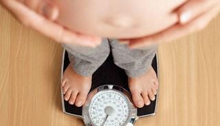 A woman with gestational diabetes standing on a scale with her exposed belly