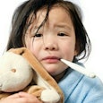 Close up of a kid holding a teddy bear and a thermometer in her mouth, going through the seven stage...