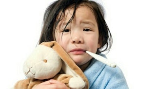 Close up of a kid holding a teddy bear and a thermometer in her mouth, going through the seven stage...
