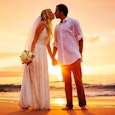 Just married husband and wife that are in love kissing each other near the sea during the sunset