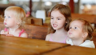Three little kids sitting next to each other at the table