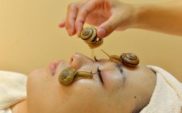 A woman lying down with eyes closed during a snail facial