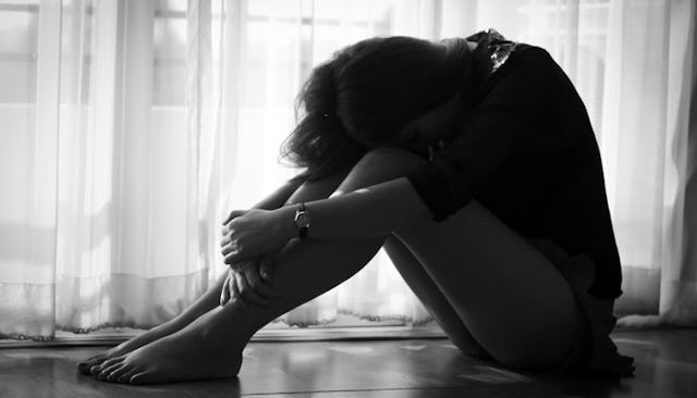A woman sobbing on the floor after being a victim of domestic violence