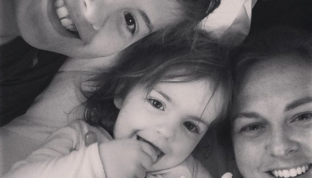 The Velveteen mother smiling with her two kids while lying on the bed