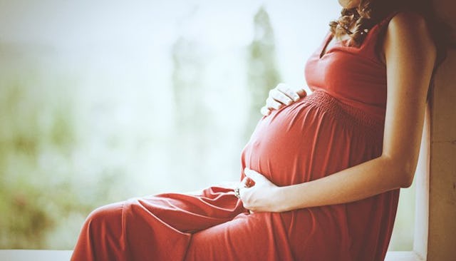 A birth mother caressing her belly while sitting outside