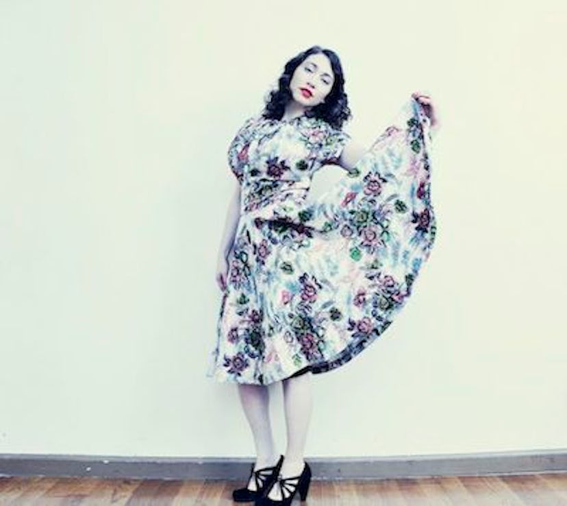 A woman in a floral dress posing and tilting her head 