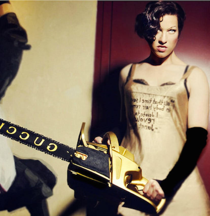Amanda Palmer in a golden apron with text on it, holding a Gucci chainsaw 