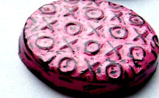A pink-colored cookie with X and O signs on it.