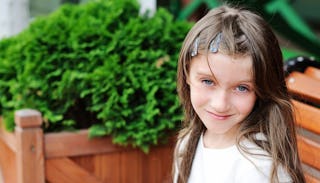 A girl sitting on a bench, while smiling and posing