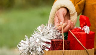 A woman's hand holding a bag full of Christmas gifts